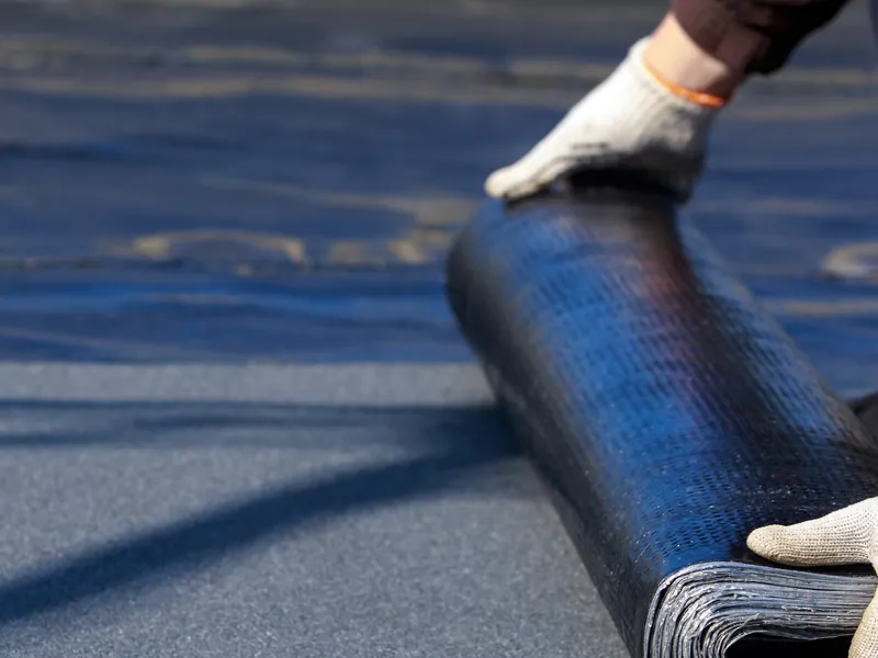 Roll of torch-on felt being laid on a flat roof