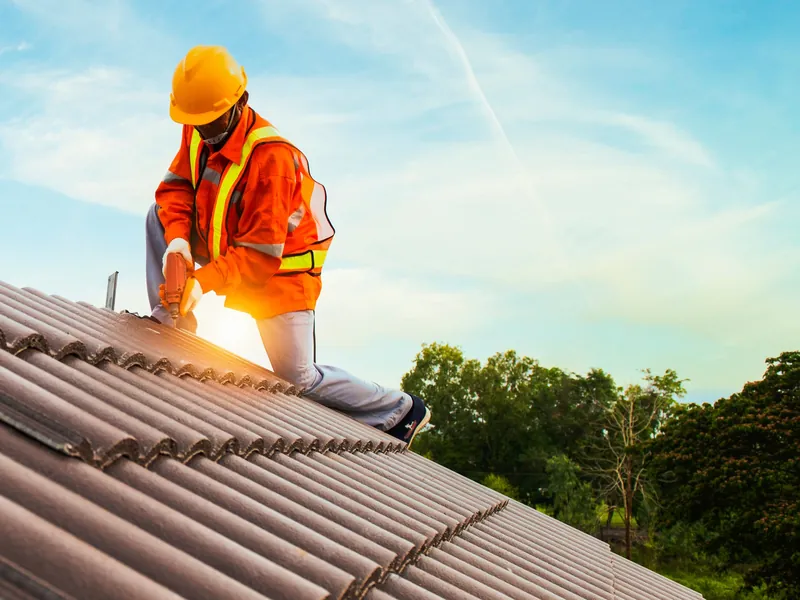 Roofer in a hard hat working on a tiled roof